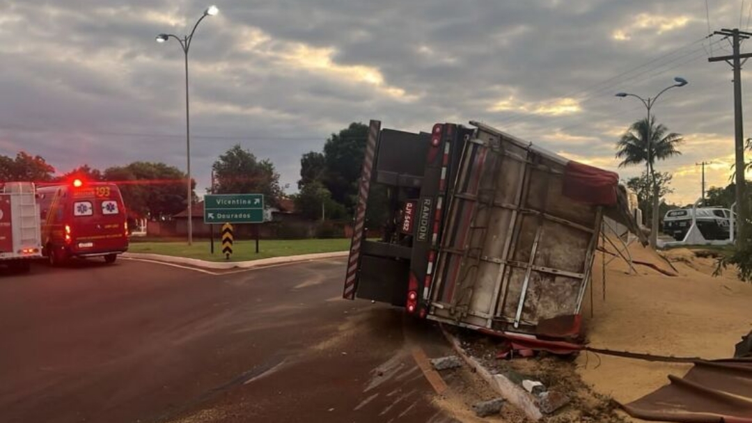 Carreta bitrem carregada com farelo de soja tomba em rotat&oacute;ria 